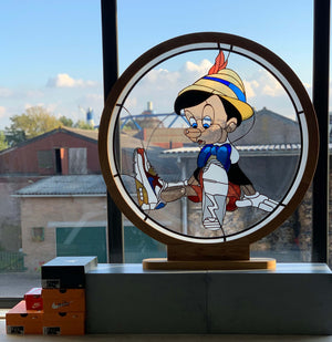 round stained glass with wooden frame depicting pinocchio in nike air max